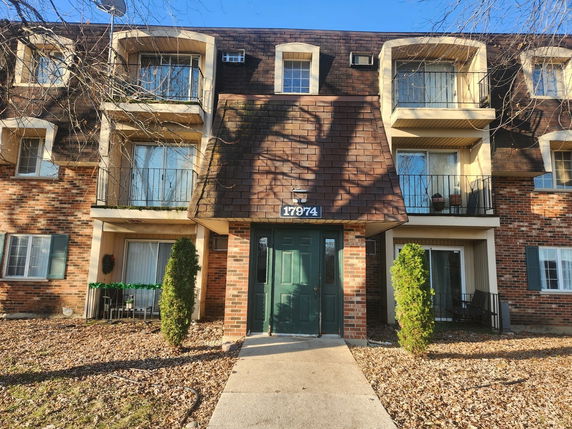Front view of a multi-story brick building with balconies and a green door entrance.