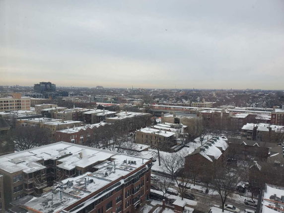 Panoramic view of a cityscape with snow-covered rooftops and buildings.