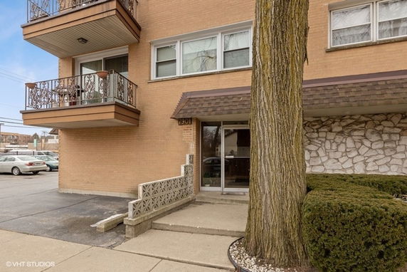 Front view of a multi-story residential building with balconies and an entrance.