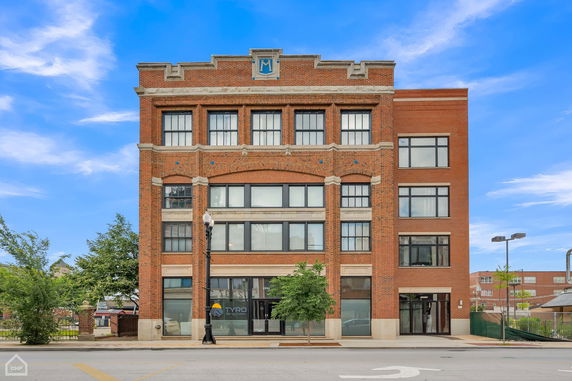 Front view of a four-story brick building with large windows.