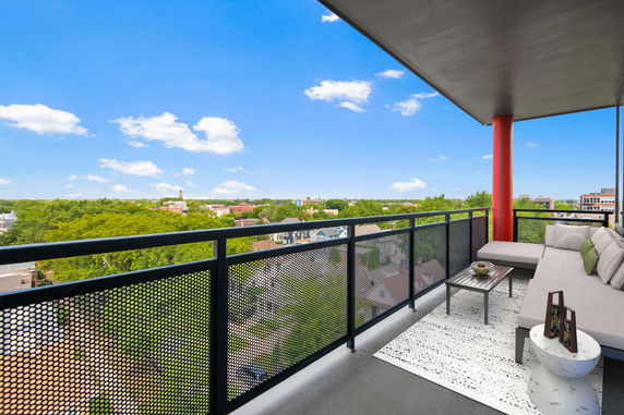 Balcony view overlooking a residential area with trees and buildings visible in the distance.