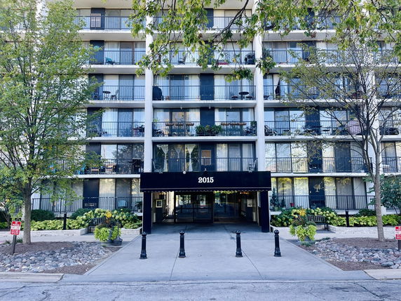 Front view of a multi-story residential building with balconies and a central entrance.