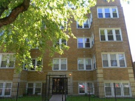 Front view of a multi-story brick apartment building with multiple windows.