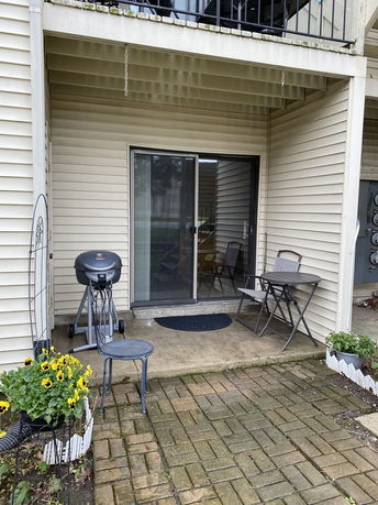 Patio area with sliding glass doors, chairs, and a grill.