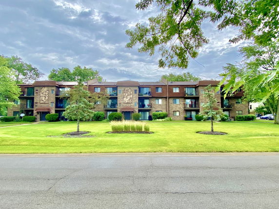 Front view of a multi-story apartment building with brick exterior and balconies.