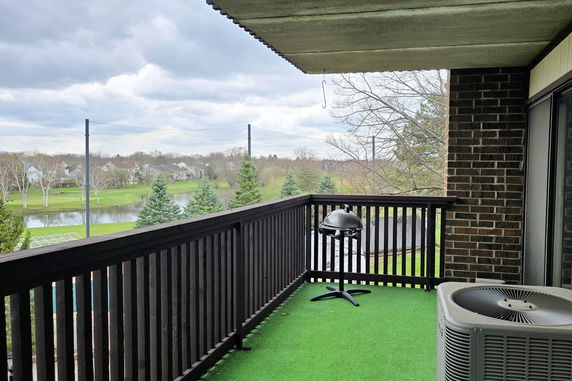 Balcony with a view of grassy landscape and a pond.