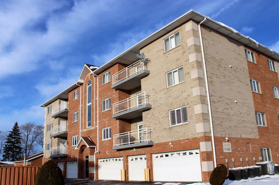 Front view of a multi-story residential building with balconies and garages.