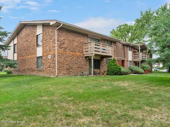 Front view of a brick apartment building with balconies and a sloped roof.
