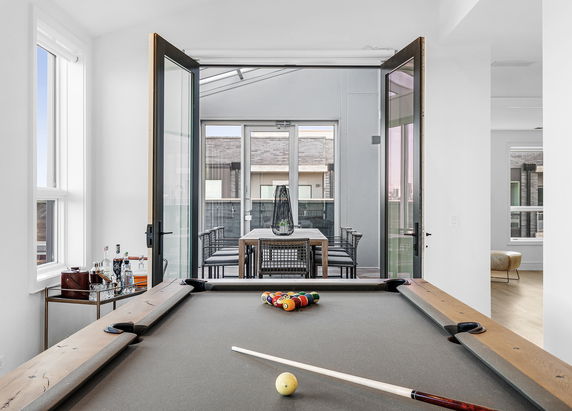 Interior view featuring a pool table and an open glass door leading to a dining area.