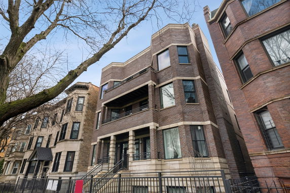 Front view of a three-story brick apartment building with balconies.