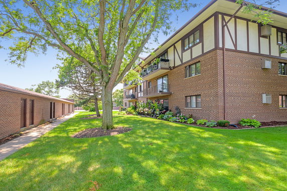 Front view of a multi-story apartment building with balconies and brick exterior.