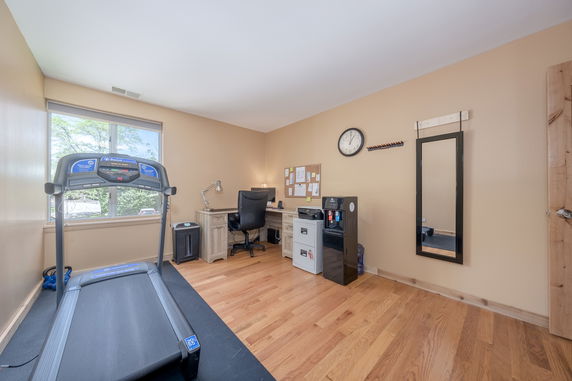 Interior view of a room with fitness and office amenities including a treadmill and desk.