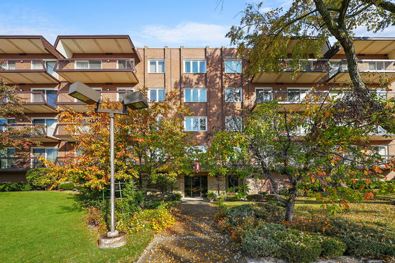 Front view of a multi-story brick apartment building with balconies.
