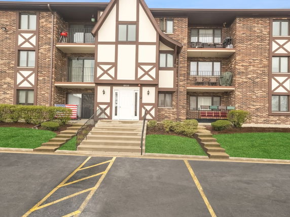 Front view of a multi-story brick apartment building with balconies.