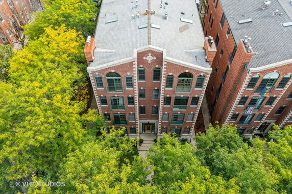 Aerial view of a brick apartment building with arched windows and a peaked roof.