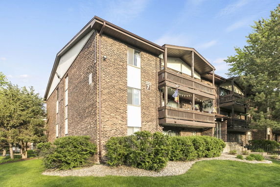 Front view of a multi-story brick apartment building with balconies.