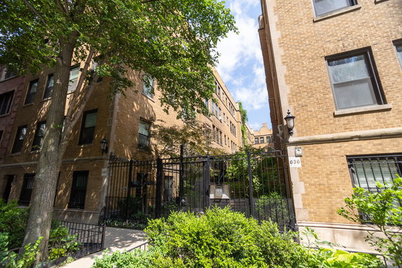 Front view of a multi-story brick building with a gated entrance.