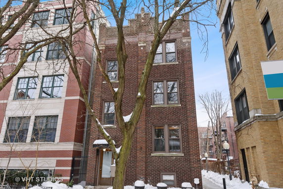 Front view of a multi-story brick building with large windows.