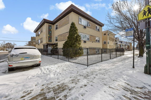 Front view of a two-story building with a fence and snow-covered surroundings.