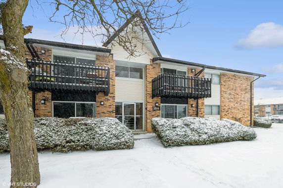 Front view of a two-story building with balconies, brick exterior, and snow-covered ground.
