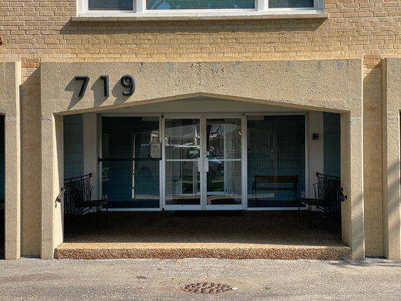 Front view of a building with a covered entrance and benches.