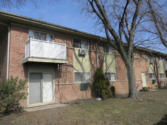 Front view of a two-story brick apartment building with a balcony.