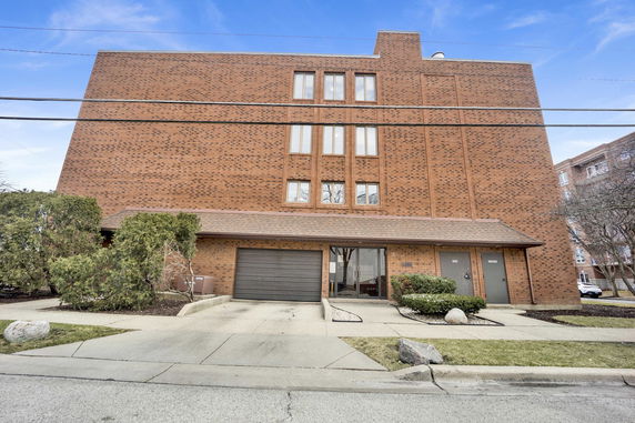 Front view of a multi-story brick building with a garage and entrance.
