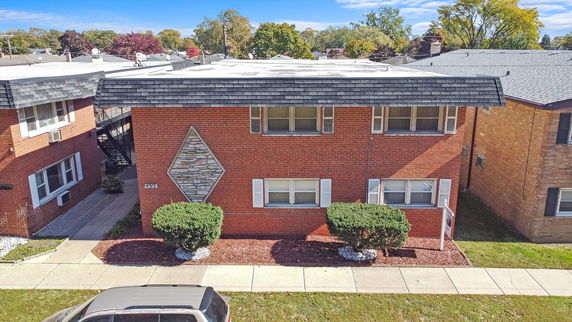 Front view of a two-story brick apartment building with a decorative stone pattern.