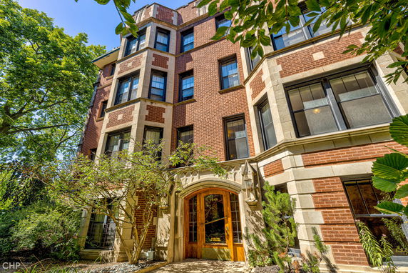 Front view of a multi-story brick building with large windows and an arched wooden entryway.