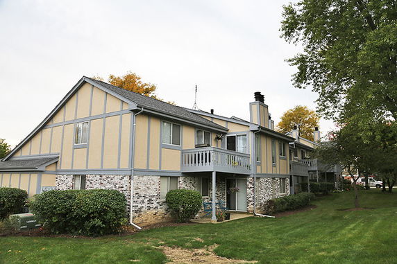 Front view of a two-story house with a balcony and brick facade.
