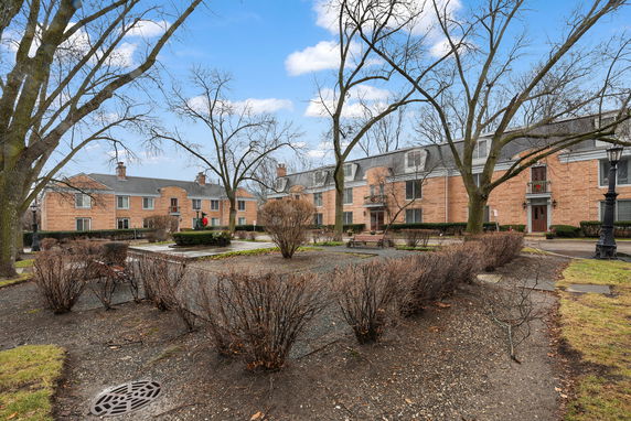Front view of a multi-story brick residential building with a dormer roof.