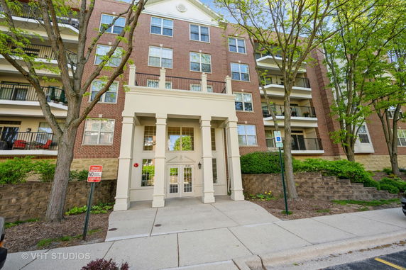 Front view of a multi-story brick apartment building with balconies.
