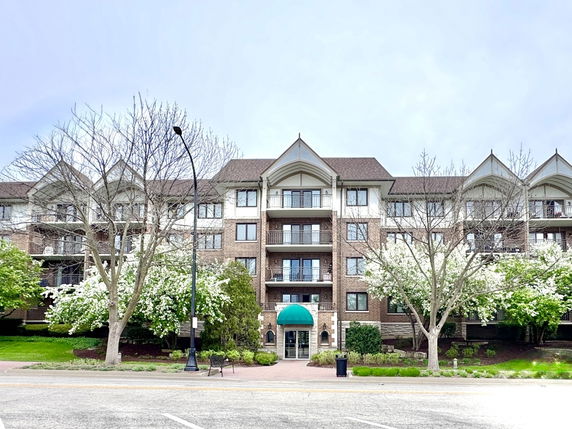 Front view of a multi-story residential building with balconies and an arched entrance.