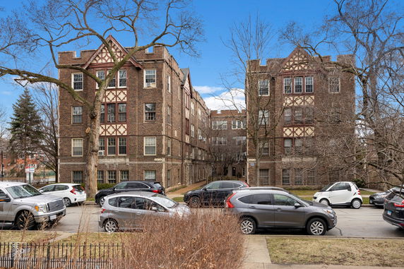 Front view of a multi-story brick apartment building with Tudor-style details.