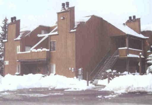 Front view of a multi-story wooden house in a snowy area.