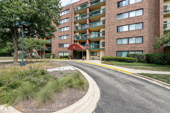 Front view of a multi-story apartment building with a brick facade and central entrance.
