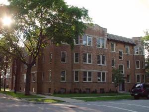 Front view of a multi-story brick building on a street corner.
