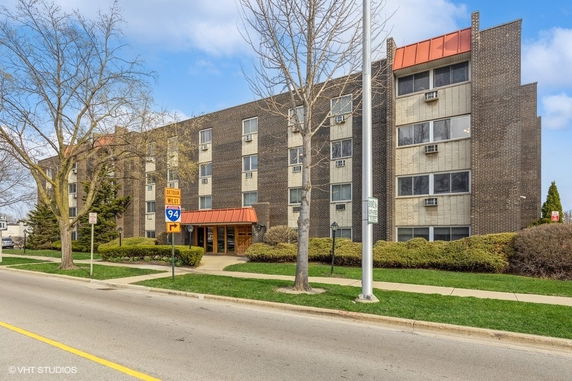 Front view of a multi-story brick building with orange accents and multiple windows.