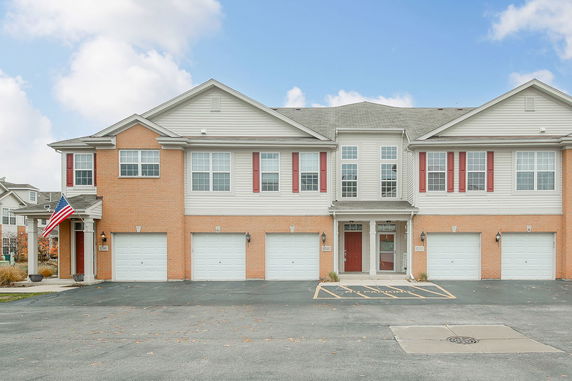 Front view of a townhouse building with multiple garages and red doors.