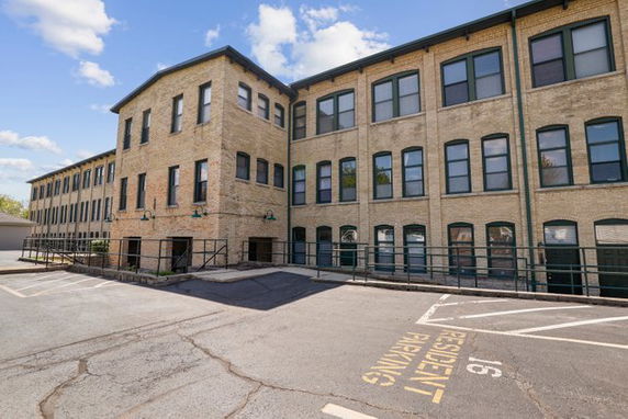 Front view of a multi-story brick building with multiple windows and a marked parking area.