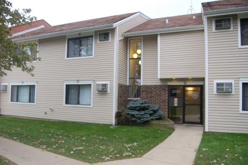 Front view of a two-story apartment building with beige siding and dark roof.