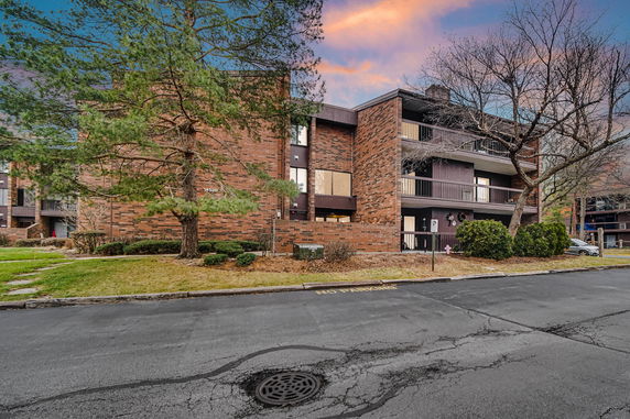 Front view of a multi-story brick apartment building with balconies.