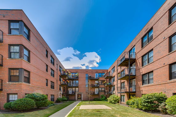 View of a brick apartment complex with multiple balconies and a central courtyard.