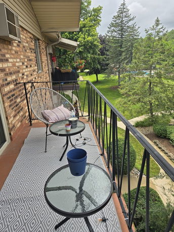 Balcony area showing a lush garden with a patio and trees.