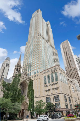 Front view of a tall skyscraper with a commercial building at its base.