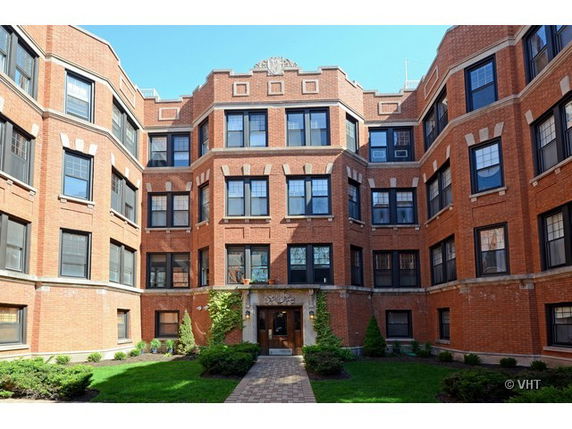 Front view of a multi-story brick building with large windows.