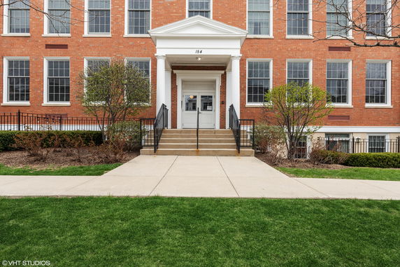 Front view of a brick building entrance with steps and columns.