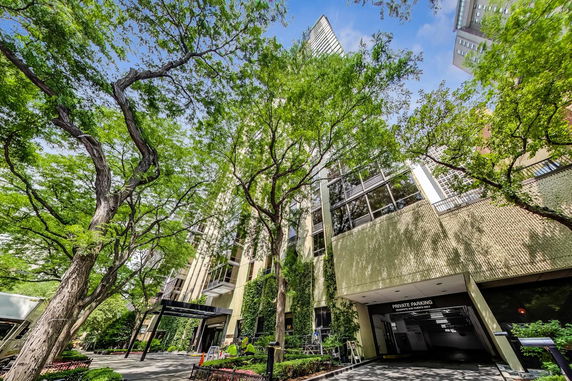 Front view of a tall building with large windows and a private parking entrance.