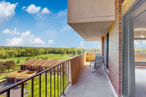 Balcony view overlooking green fields and distant horizon.