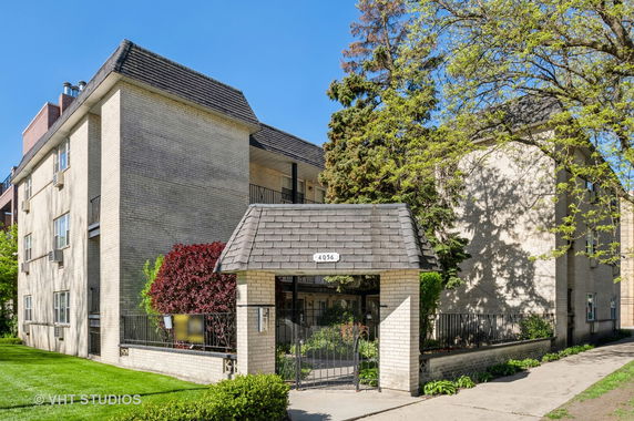 Front view of a multi-story residential building with a gated entrance.